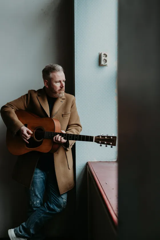 Ed Struijlaart met gitaar bij het raam